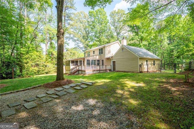 back of house featuring a sunroom, fence, a chimney, a lawn, and a deck
