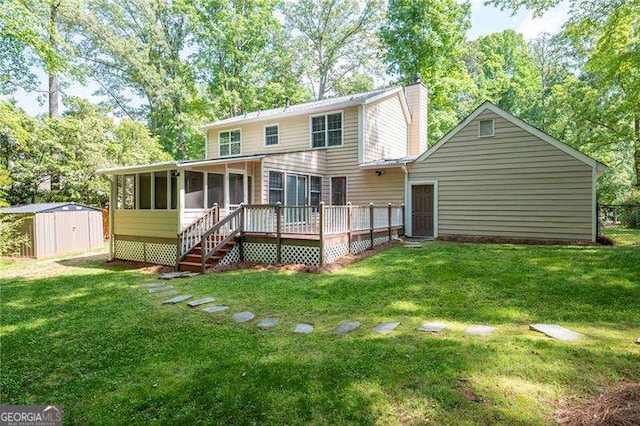 rear view of property with a deck, an outdoor structure, a storage unit, a lawn, and a sunroom