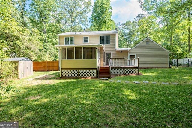 back of house with a lawn, a sunroom, fence private yard, a wooden deck, and a storage unit