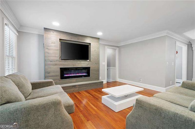 living area featuring wood finished floors, ornamental molding, recessed lighting, baseboards, and a glass covered fireplace