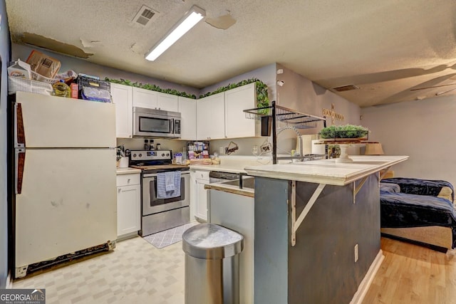 172 Evergreen Dr, Jackson, GA 30233 - kitchen with light countertops, a textured ceiling, stainless steel appliances, white cabinetry, and a peninsula