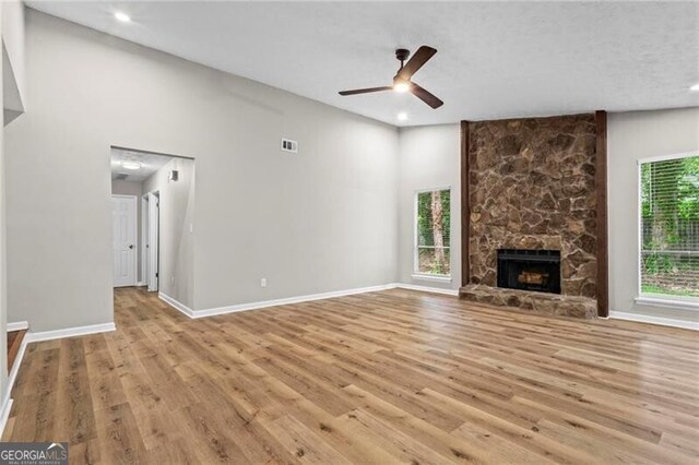 unfurnished living room featuring light wood-style floors, a ceiling fan, recessed lighting, a stone fireplace, and baseboards