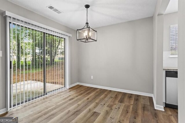 unfurnished dining area featuring a chandelier, wood finished floors, and baseboards