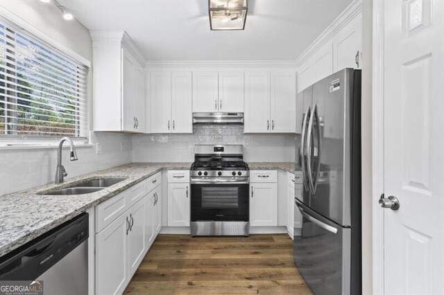 kitchen with stainless steel appliances, a sink, under cabinet range hood, white cabinets, and dark wood-style floors