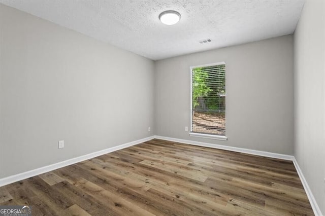 unfurnished room with wood finished floors, a textured ceiling, and baseboards