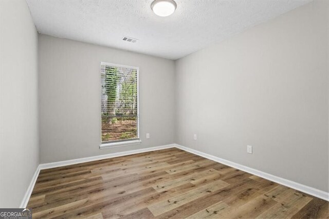 empty room featuring wood finished floors, baseboards, and a textured ceiling