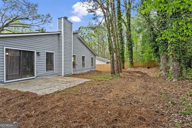 rear view of house featuring a patio, a chimney, and fence