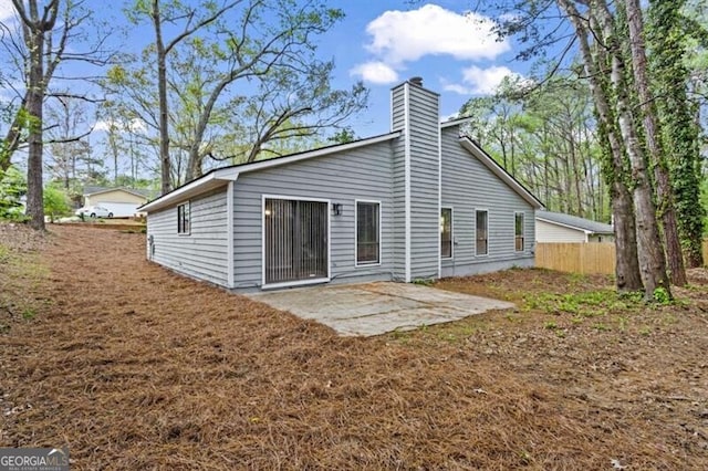 rear view of property with a patio, a chimney, and fence