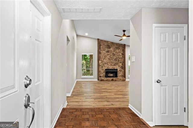 entrance foyer with baseboards, vaulted ceiling, a textured ceiling, and a fireplace