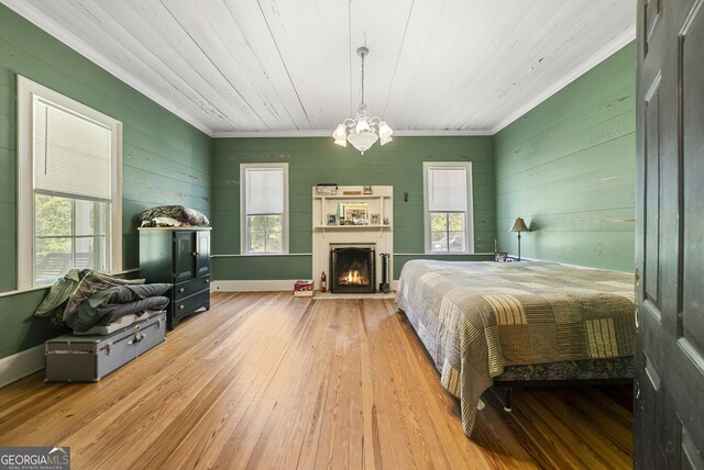 bedroom featuring hardwood / wood-style flooring, an inviting chandelier, ornamental molding, and multiple windows