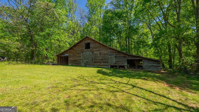 back of house featuring a lawn, a barn, and an outbuilding