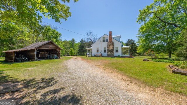 view of front of house with a pole building, a chimney, driveway, and a front lawn