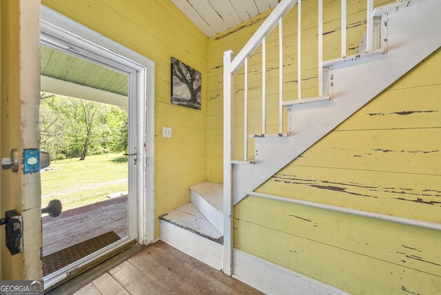doorway with wood walls and wood finished floors