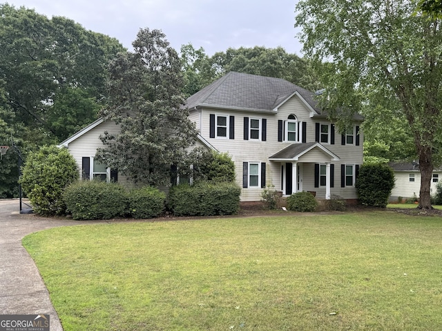 colonial home featuring a front lawn and roof with shingles