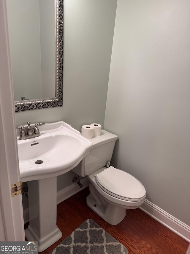 bathroom with baseboards, toilet, and wood finished floors