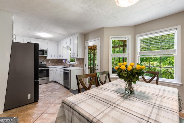 588 Peachtree Dr SE, White, GA 30184 - kitchen featuring stainless steel appliances, tasteful backsplash, light countertops, light tile patterned floors, and white cabinetry