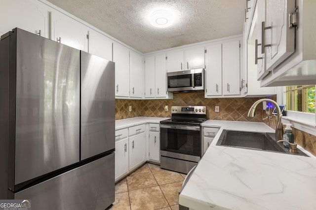 588 Peachtree Dr SE, White, GA 30184 - kitchen with stainless steel appliances, a textured ceiling, white cabinets, light stone countertops, and decorative backsplash