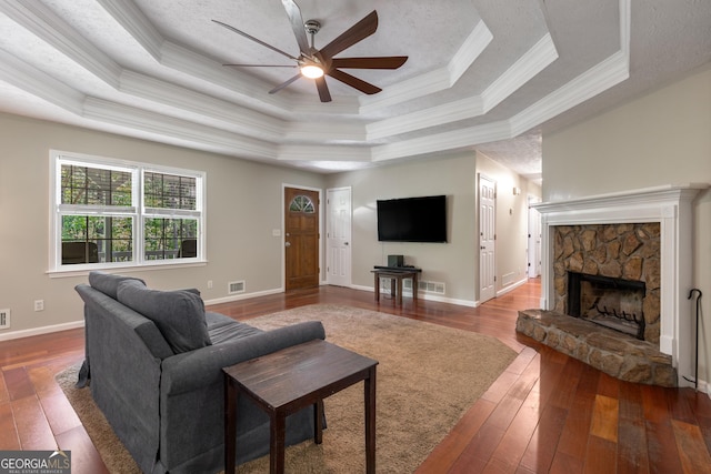 588 Peachtree Dr SE, White, GA 30184 - living room featuring a tray ceiling, ornamental molding, a ceiling fan, hardwood / wood-style flooring, and a stone fireplace
