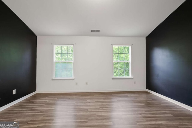 5244 Carrington Park Dr, Powder Springs, GA 30127 - spare room featuring plenty of natural light, vaulted ceiling, wood finished floors, and visible vents