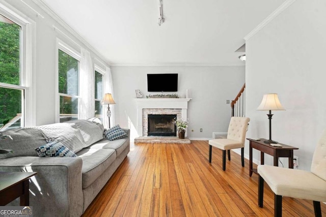 1126 Gate Post Ct, Powder Springs, GA 30127 - living area featuring track lighting, ornamental molding, stairs, a brick fireplace, and hardwood / wood-style floors