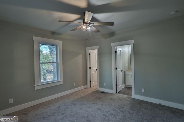 unfurnished bedroom featuring carpet floors, baseboards, ensuite bathroom, and visible vents