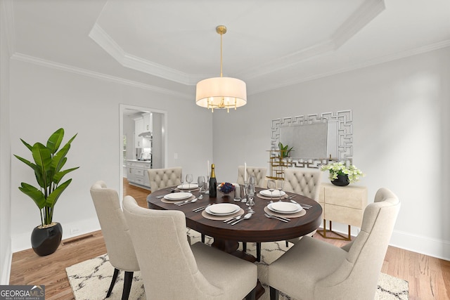 dining room featuring ornamental molding, a tray ceiling, wood finished floors, and a chandelier