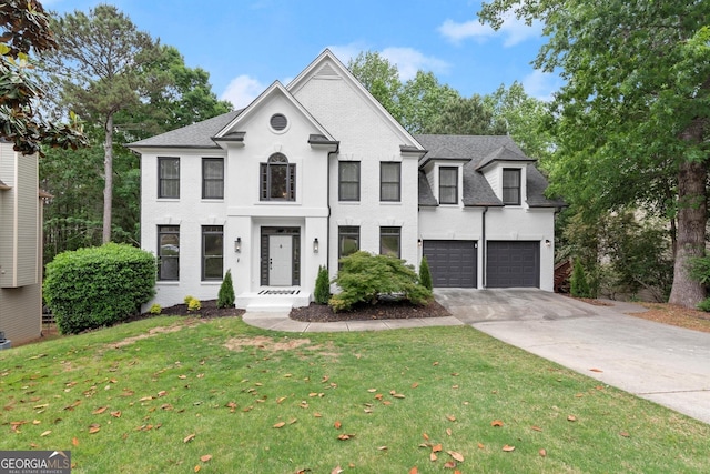 colonial house with a garage, concrete driveway, a shingled roof, a front yard, and brick siding
