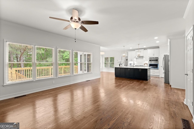 unfurnished living room with visible vents, wood finished floors, and ceiling fan