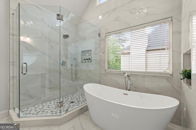 bathroom with a shower stall, tile walls, marble finish floor, and a freestanding tub