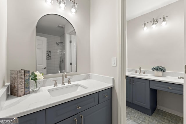 bathroom with speckled floor, visible vents, vanity, and a tile shower
