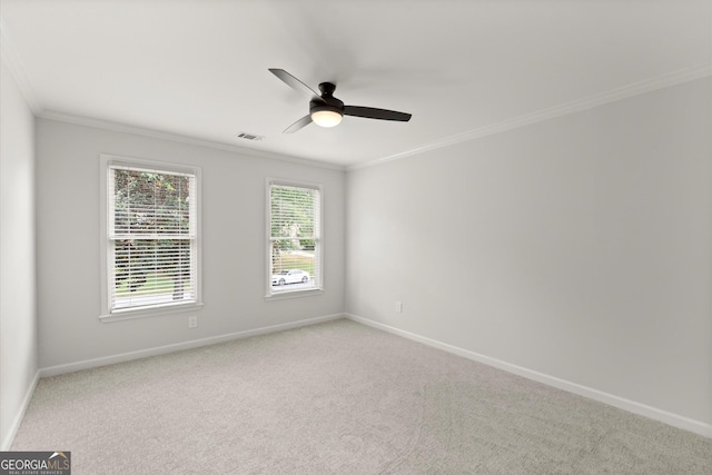 carpeted empty room with crown molding, baseboards, ceiling fan, and visible vents