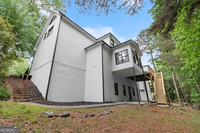 back of house featuring stairway, a patio, and a wooden deck