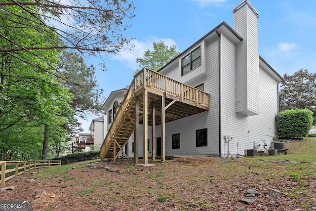 back of house featuring stairs, fence, a wooden deck, a chimney, and central AC unit