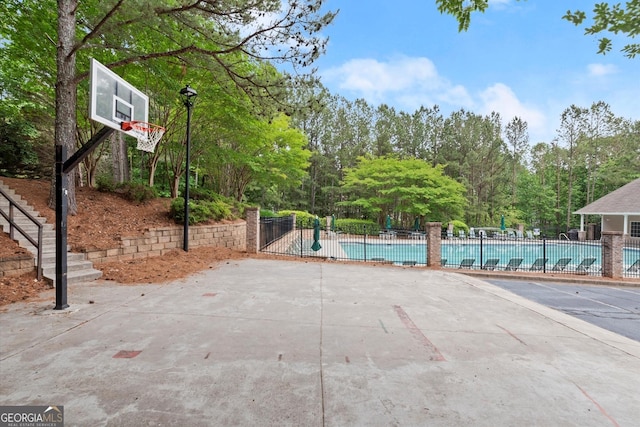 view of sport court featuring fence and a community pool
