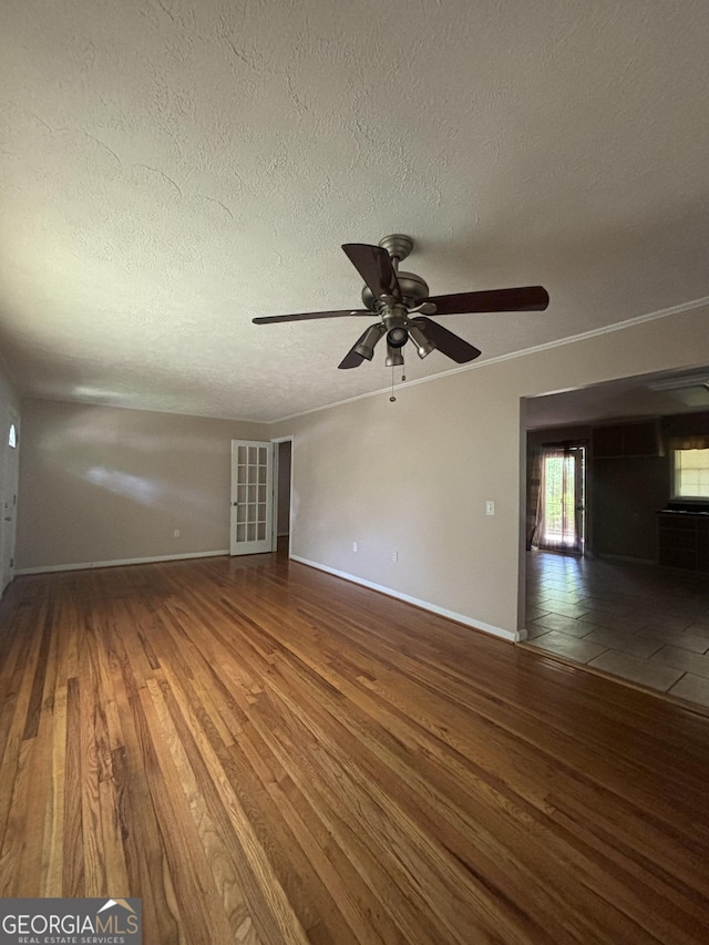 9163 Fair St SW, Covington, GA 30014 - unfurnished living room featuring baseboards, a textured ceiling, ceiling fan, and wood finished floors