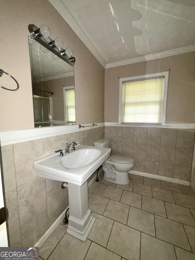 9163 Fair St SW, Covington, GA 30014 - bathroom with crown molding, tile patterned flooring, wainscoting, toilet, and tile walls