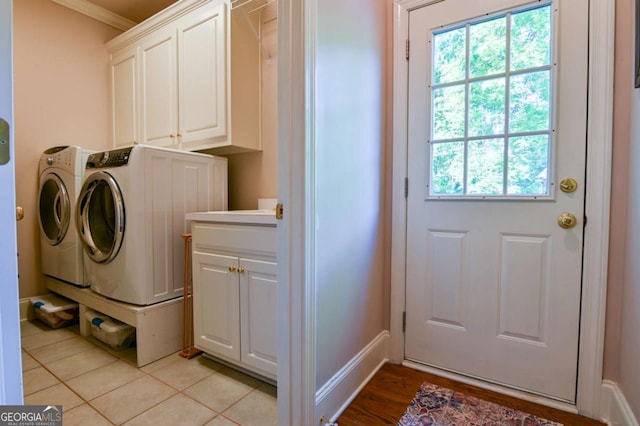 washroom featuring baseboards, ornamental molding, independent washer and dryer, and cabinet space