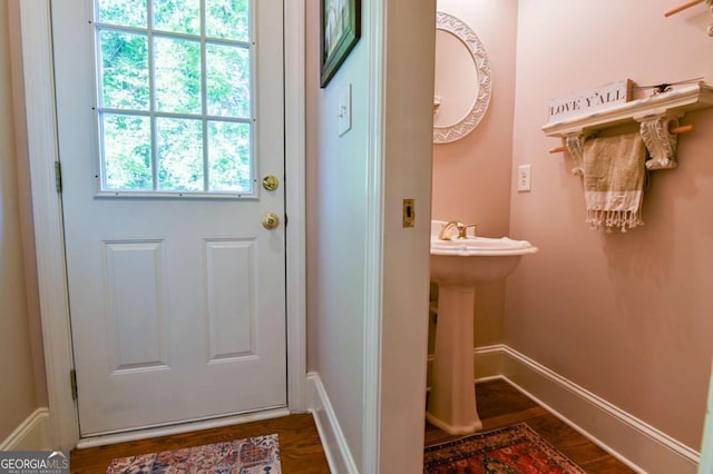 doorway to outside featuring baseboards and dark wood-type flooring