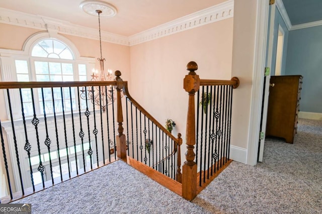 stairway featuring carpet floors, baseboards, crown molding, and an inviting chandelier