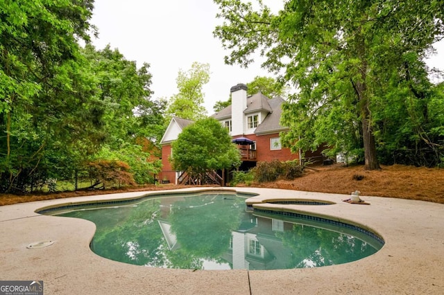 outdoor pool featuring a wooden deck and an in ground hot tub