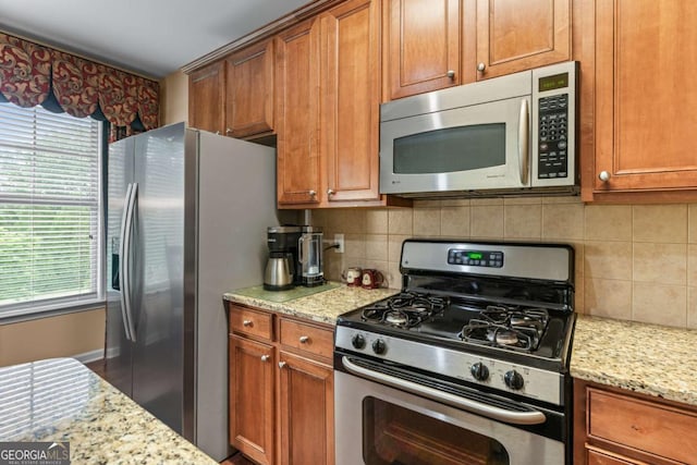 661 Village Field Ct NW, Suwanee, GA 30024 - kitchen with decorative backsplash, stainless steel appliances, light stone countertops, and brown cabinetry