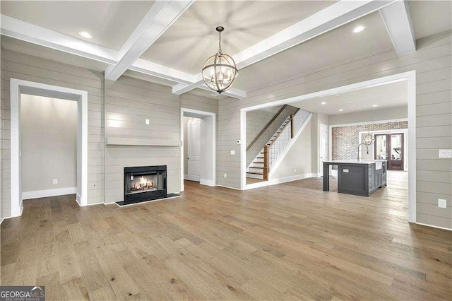 7235 Cordery Rd, Cumming, GA 30040 - unfurnished living room featuring beamed ceiling, stairs, wood finished floors, and a chandelier