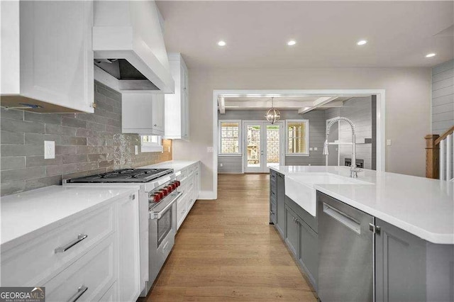 7235 Cordery Rd, Cumming, GA 30040 - kitchen featuring light wood-type flooring, light countertops, custom range hood, a sink, and appliances with stainless steel finishes