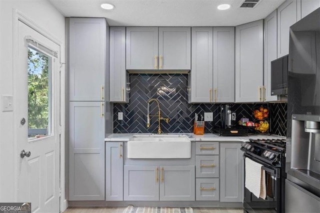 kitchen featuring black range with gas cooktop, a sink, and gray cabinets