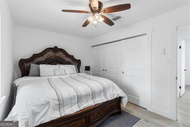 bedroom with ceiling fan, a closet, light wood-style flooring, and visible vents