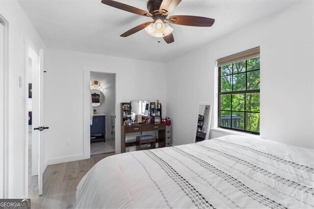 bedroom featuring baseboards, ceiling fan, ensuite bathroom, and wood finished floors