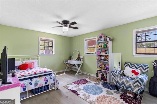 bedroom featuring baseboards, wood finished floors, and multiple windows