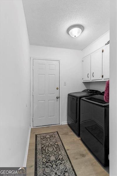 laundry room with baseboards, light wood-style flooring, cabinet space, and washer and dryer