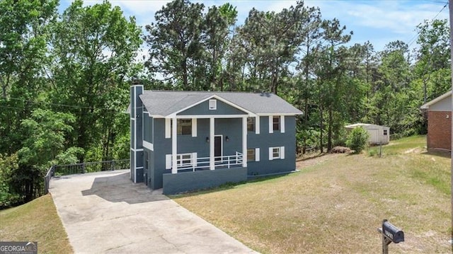 raised ranch with a porch, driveway, an outdoor structure, and a front yard