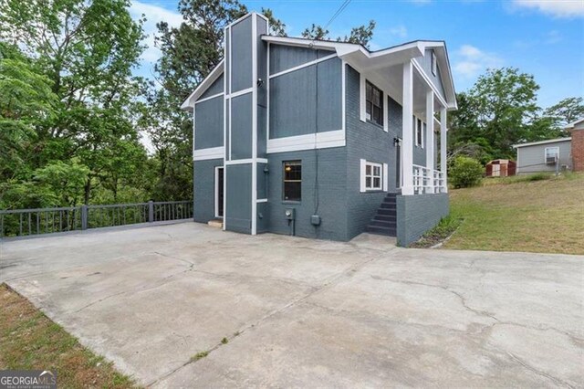exterior space with a lawn, brick siding, driveway, and fence